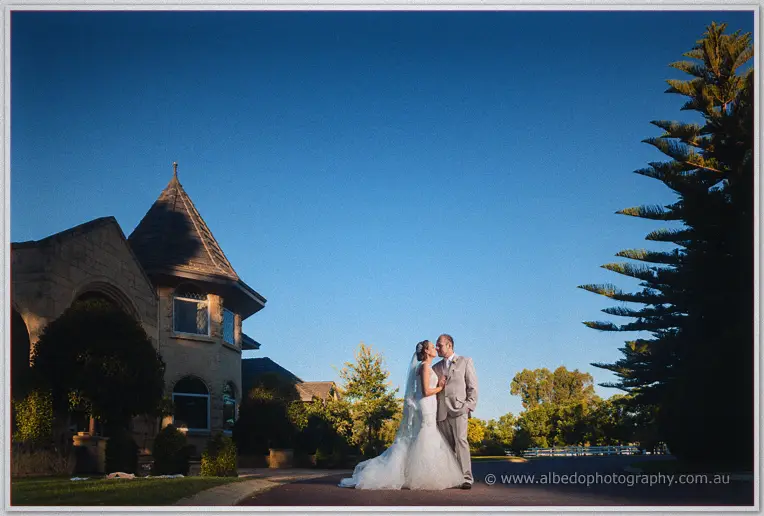 Katelyn and Matt kissing on the drive outside Brookleigh's turreted stone homestead at dusk
