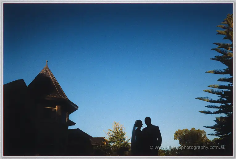 Silhouette of the couple beneath Brookleigh's turret against a deepening blue evening sky