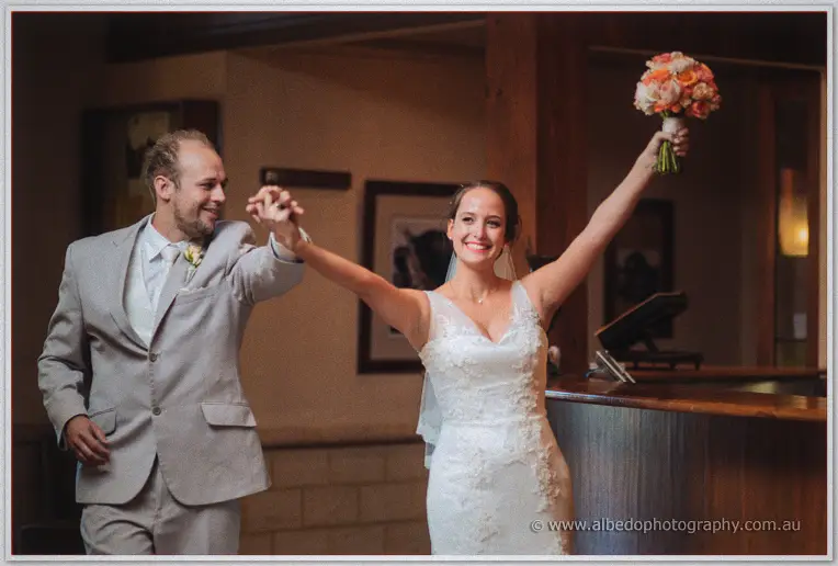 Katelyn raising her bouquet triumphantly as she and Matt make their reception entrance
