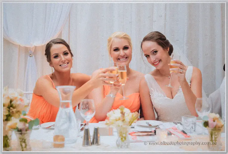 Katelyn and her bridesmaids toasting with champagne flutes along the draped bridal table