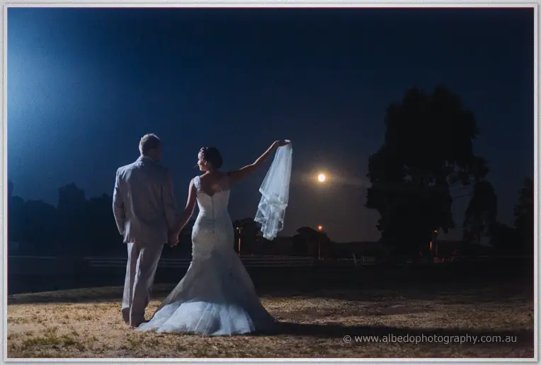 Katelyn swings her veil toward a rising moon as she and Matt stroll the twilight paddock