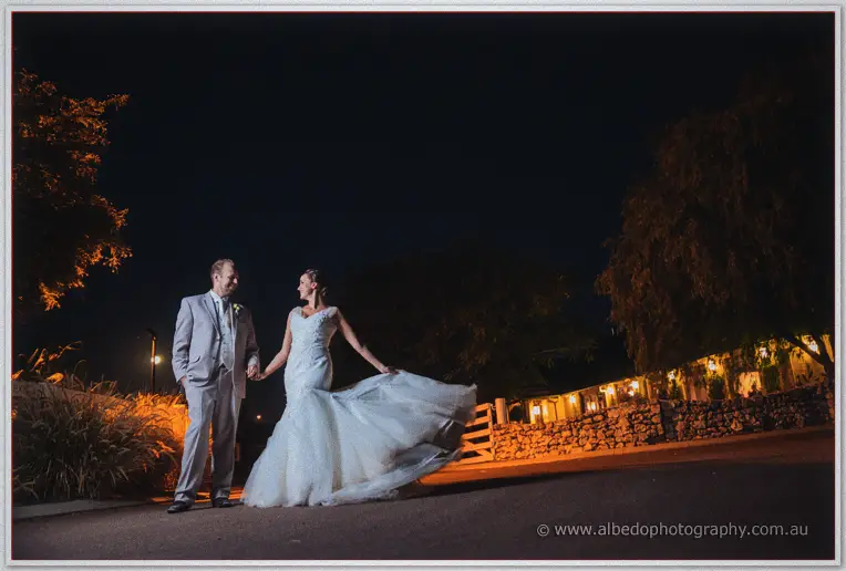 Katelyn swirls her full skirt while holding hands with Matt beside lamplit stone walls at night