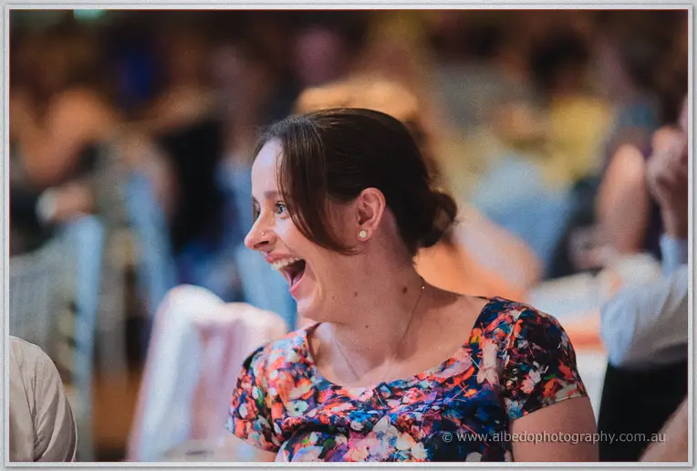 A guest in a floral dress laughs heartily during speeches at the Brookleigh reception