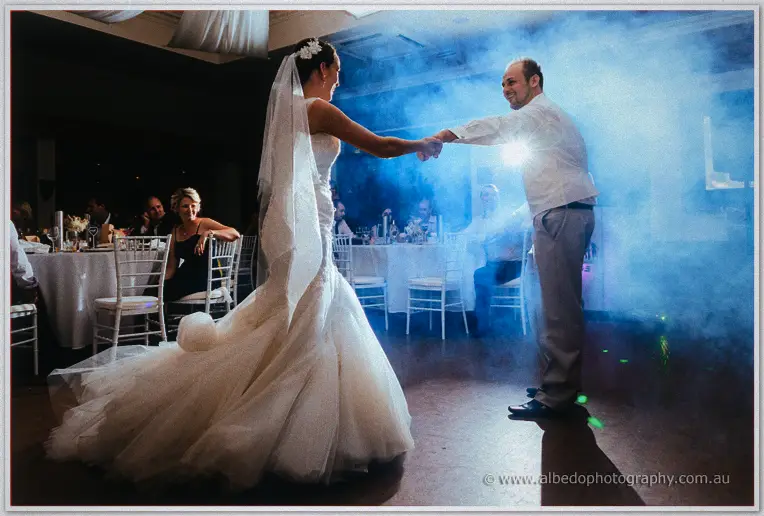 Matt pulls Katelyn close across the dance floor through glowing fog and low light