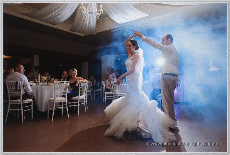 Matt twirls Katelyn beneath a chandelier as fog swirls across the reception floor