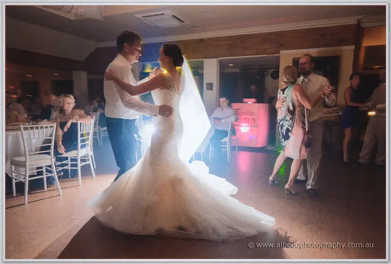 Katelyn's gown flares as Matt dances her past guests under warm reception lighting