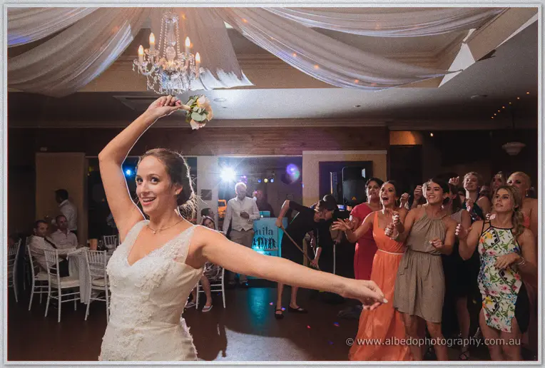 Katelyn winds up to toss her bouquet to a line of eager guests at the reception