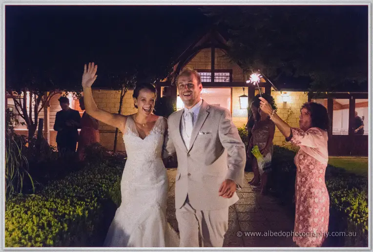 Katelyn waves to guests as she and Matt exit the lamplit homestead past a woman holding a sparkler