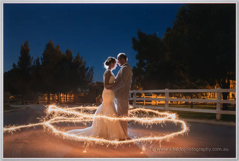 Katelyn and Matt stand forehead to forehead inside a glowing ring of sparkler light at night