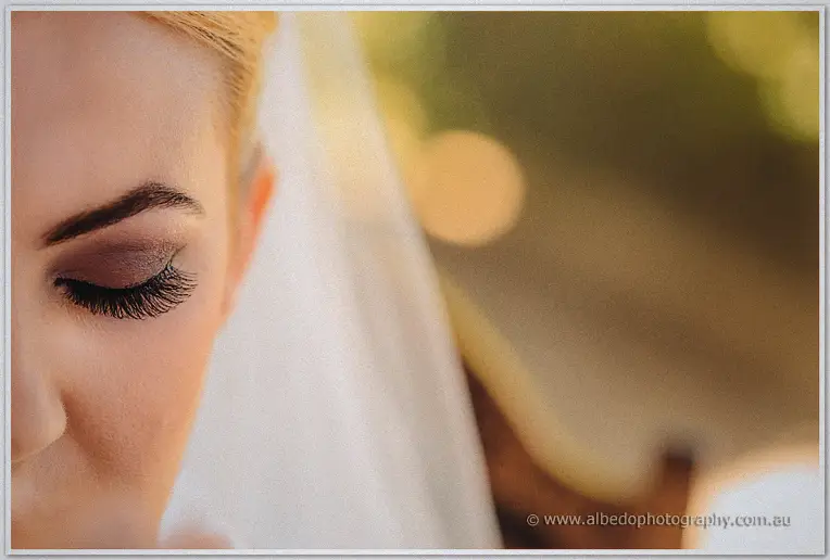 Close-up of Teigan's eye with mauve shadow and long lashes beneath her veil in golden light