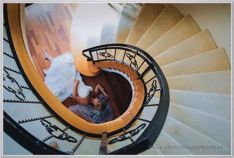 Viewed from above, Teigan's veil and gown swirl down a timber spiral staircase