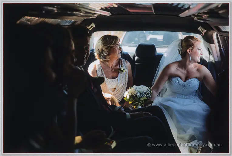 Teigan rides the limousine with her mother and bridal party, chatting in bright daylight
