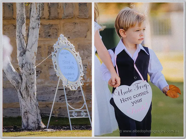Wedding sign for Troy and Teigan on an easel beside a page boy carrying a heart sign