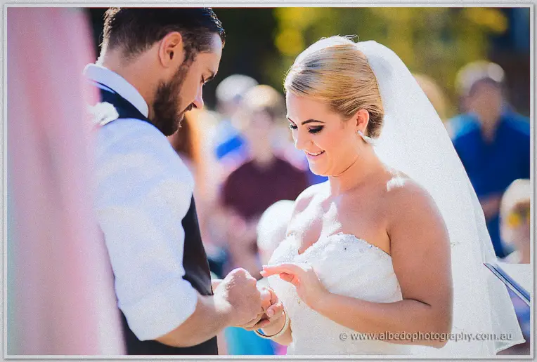 Teigan smiles down as Troy slides the ring onto her finger at the arbour