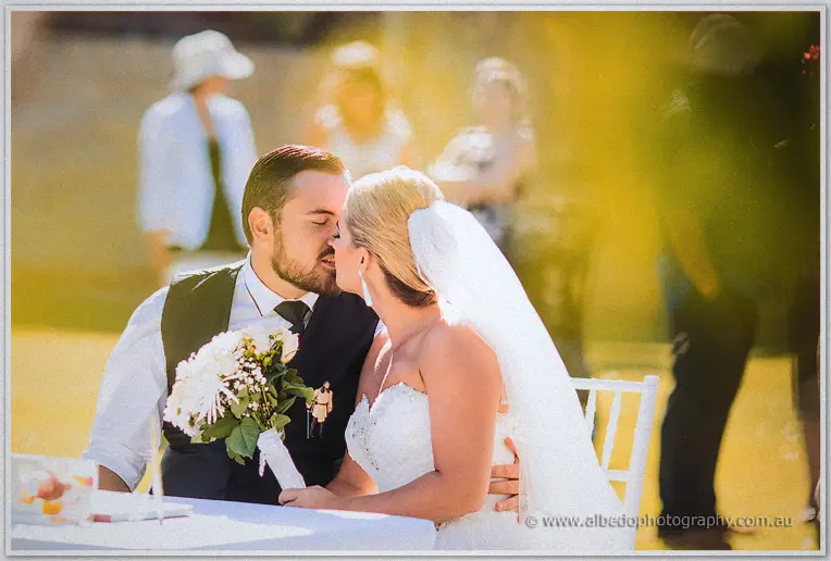 Sealed with a kiss at the signing table, Teigan holding her white bouquet beside Troy