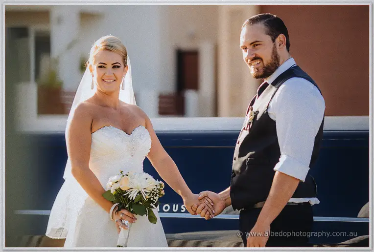 Troy grins holding Teigan's hand beside the limousine in warm afternoon light