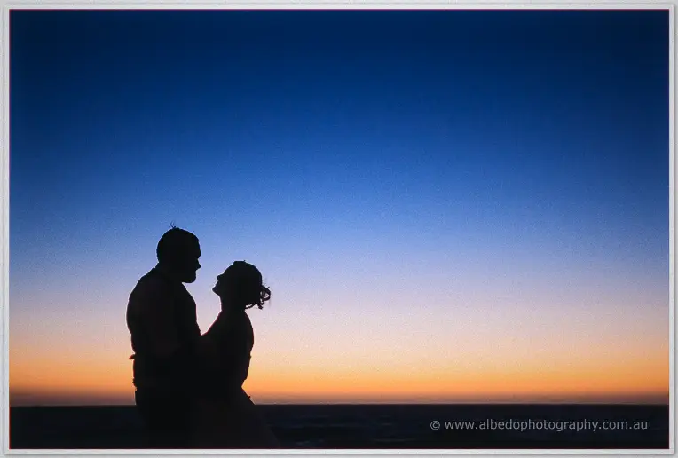 Pure silhouette of the pair facing each other against a gradient dusk sky over the sea