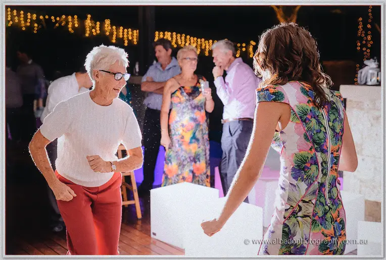 A silver-haired guest dances with fists pumping as a young woman in floral joins in