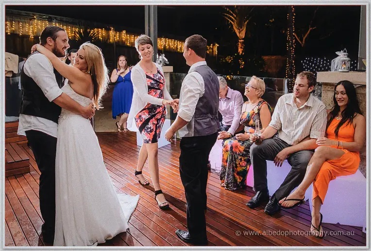 Two couples share the timber dance floor while seated guests grin from glowing cube seats