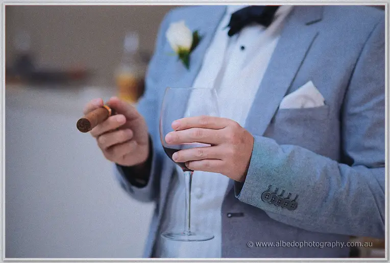 Michael twirls a cigar with one hand and a glass of shiraz in the other.