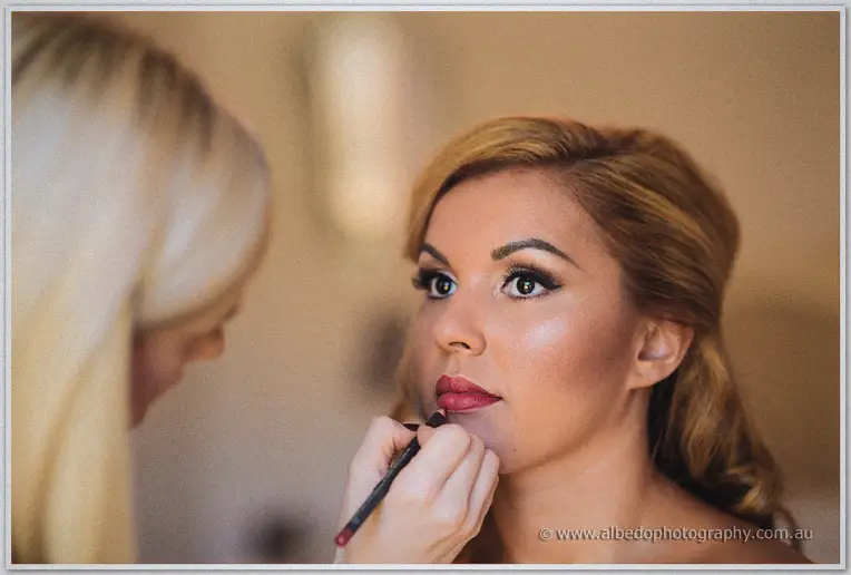 A makeup artist touches up Jasmine's bold red lip before the ceremony.