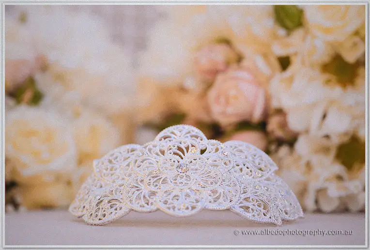 Delicate silver filigree bridal comb set against blurred cream and blush roses in soft warm light