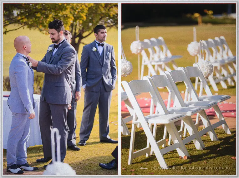 Groomsman pinning the groom's boutonniere beside rows of white folding chairs with pom-pom aisle markers