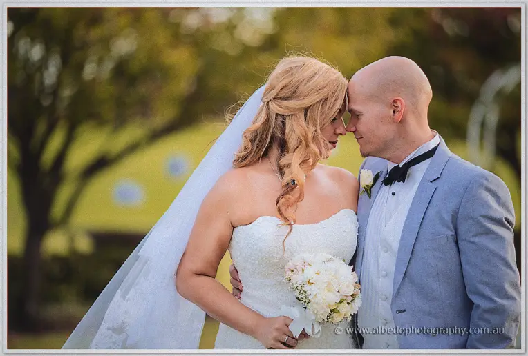Jasmine and Michael touch foreheads at golden hour, bouquet of white blooms in hand.