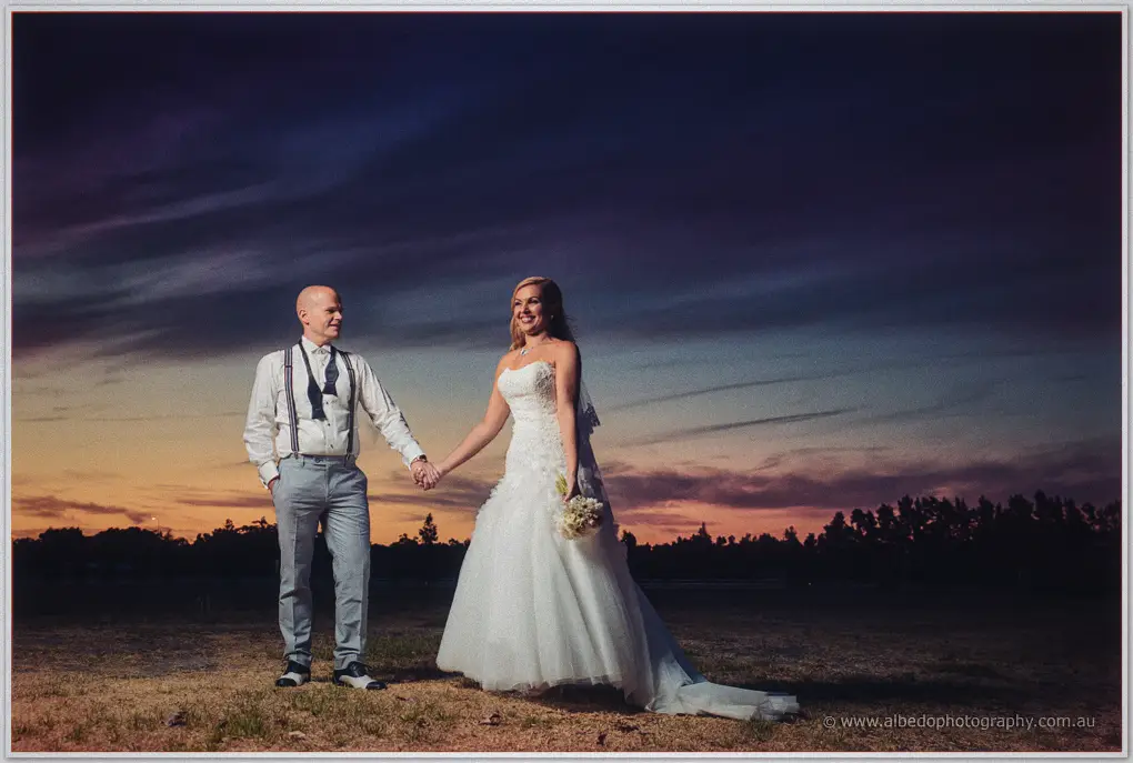 Jasmine and Michael hold hands under a deep sunset sky on the lawns at Sandalford Wines.