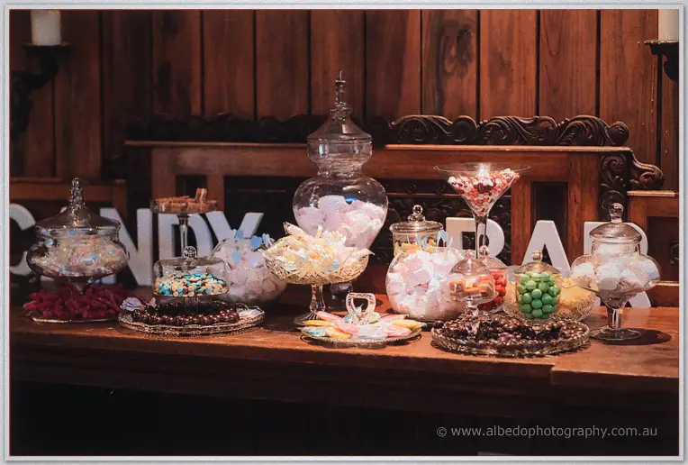 Lolly buffet in glass jars and apothecary vessels on a timber sideboard at the reception.