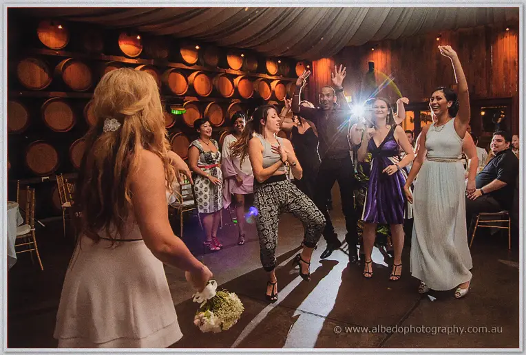 Bouquet in hand, Jasmine turns to face guests dancing with raised arms in the barrel hall.