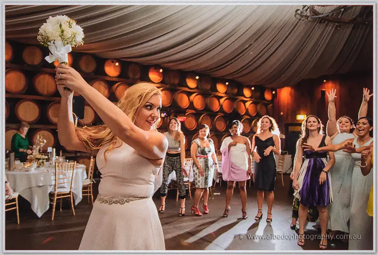 Jasmine swings the bouquet high over her shoulder as laughing single women line up behind her.