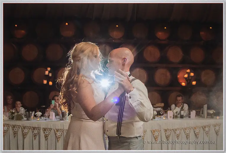 Jasmine rests her hand on Michael's shoulder during a slow, flare-lit dance as guests film from their seats.