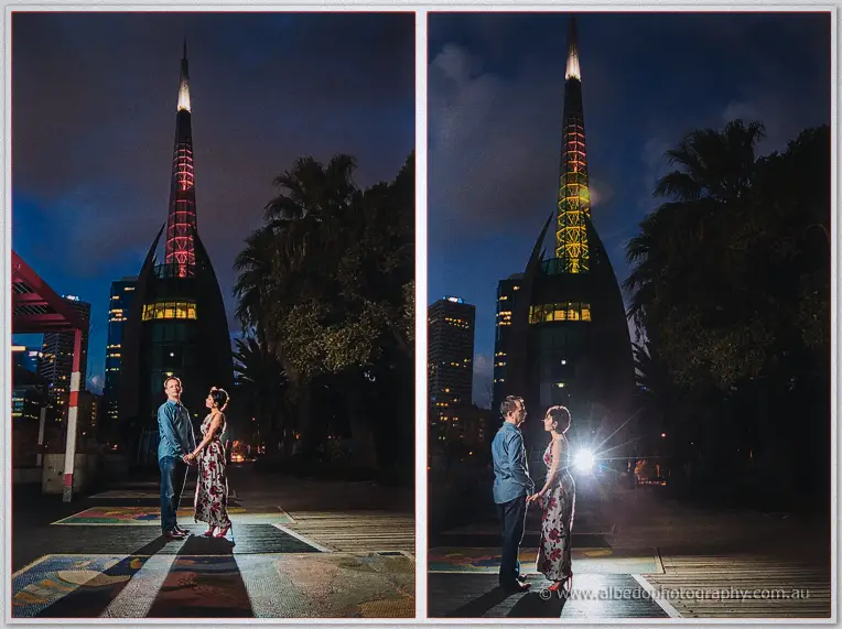 Loan and Alex hold hands at night beneath the illuminated spire of the Perth bell tower