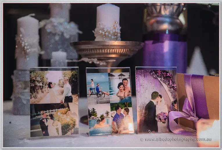 Framed couple photos and pearl-studded candles decorate the reception table in purple light