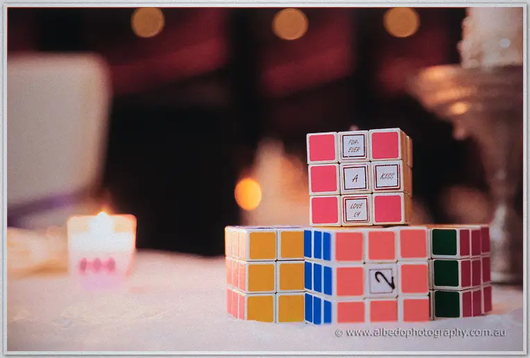 Colourful rubik's cube table numbers sit beside candles on the lace-draped table