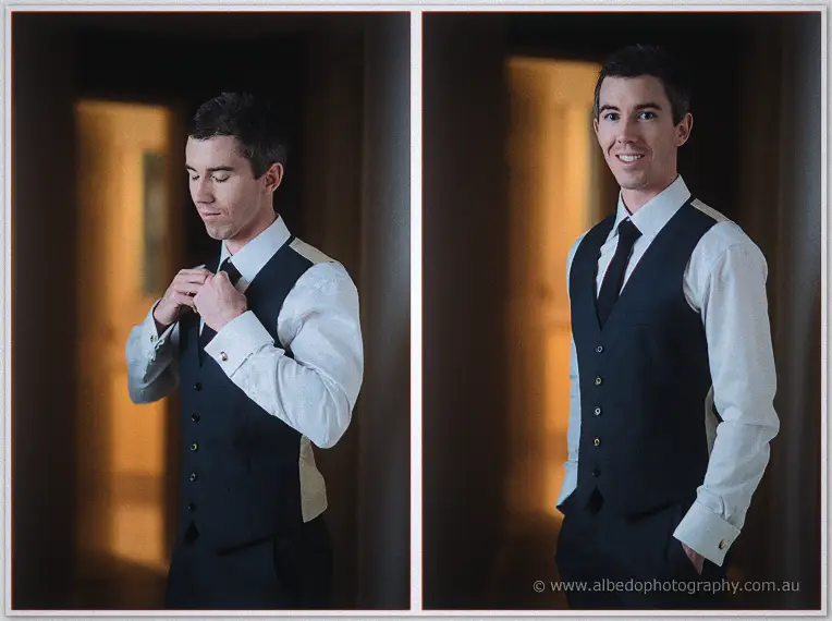 Diptych of the groom fastening his tie then smiling in a navy vest by a glowing doorway