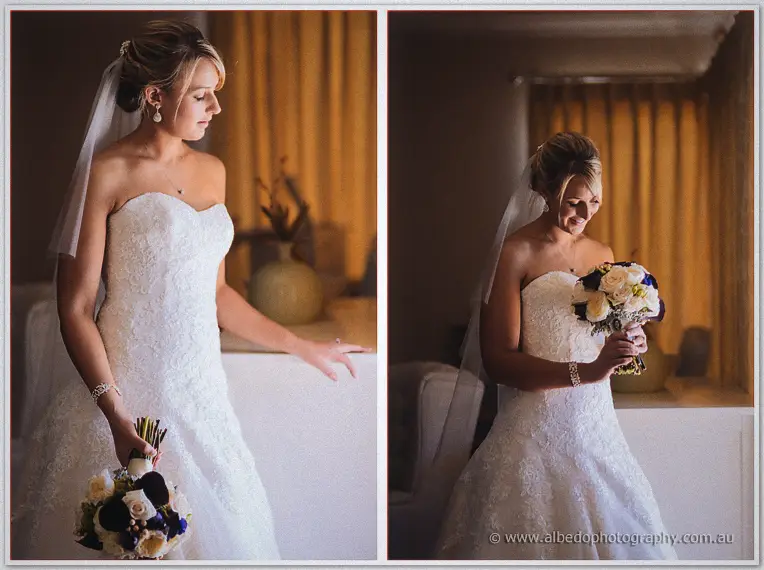 Lauren holds her white and navy bouquet in warm lamplight, glancing down with a smile