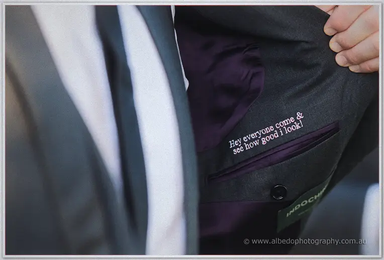 Close-up of embroidered pink lettering stitched inside a groom's grey suit jacket lining