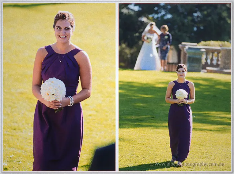A bridesmaid in deep purple walks the aisle holding white peonies, Lauren arriving behind