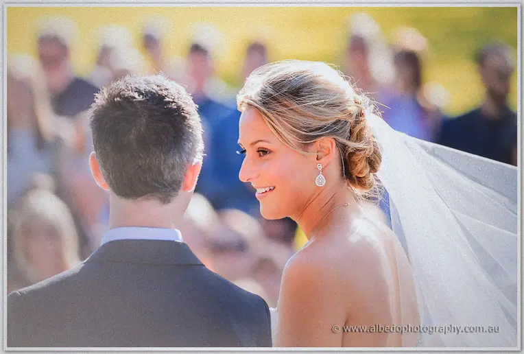 Lauren turns to Ryan with a smile, veil lifting in the breeze during vows
