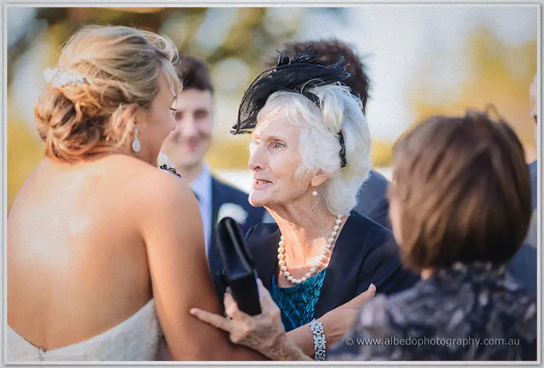 Lauren greets a grandmother in pearls and a black fascinator after the ceremony