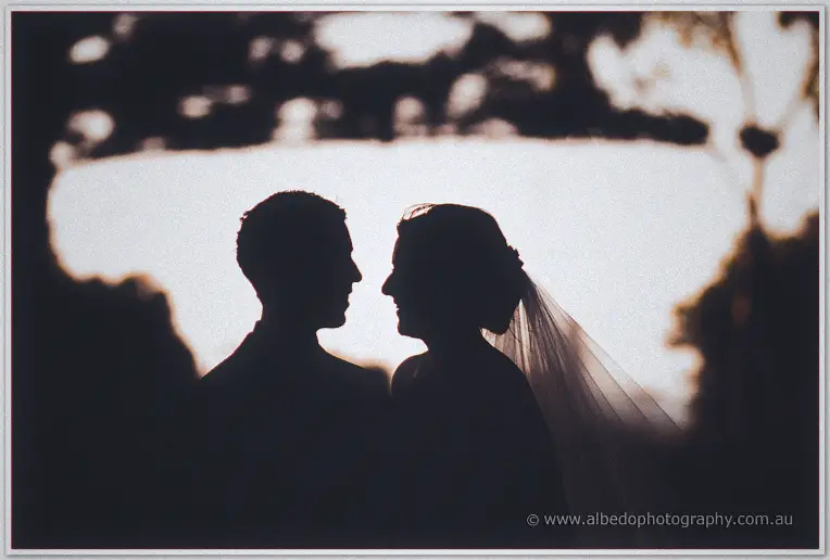 Silhouetted against the fading light, Lauren and Ryan nearly touch, veil drifting