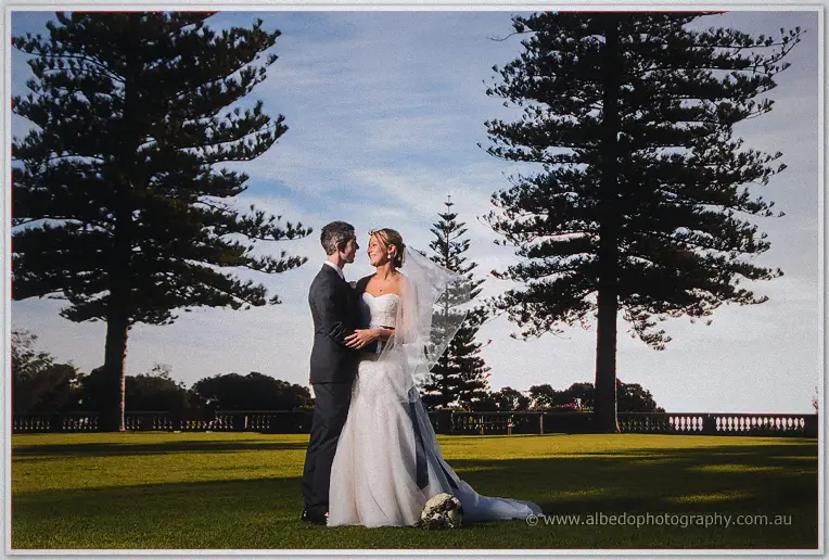 Lauren and Ryan stand forehead to forehead on the lawns, veil lifting in the breeze between pines