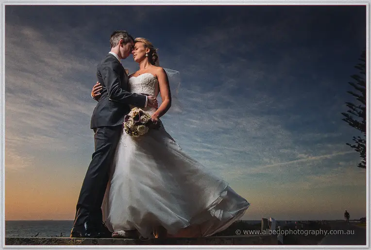 Lauren and Ryan press foreheads together against a moody twilight sky over the water