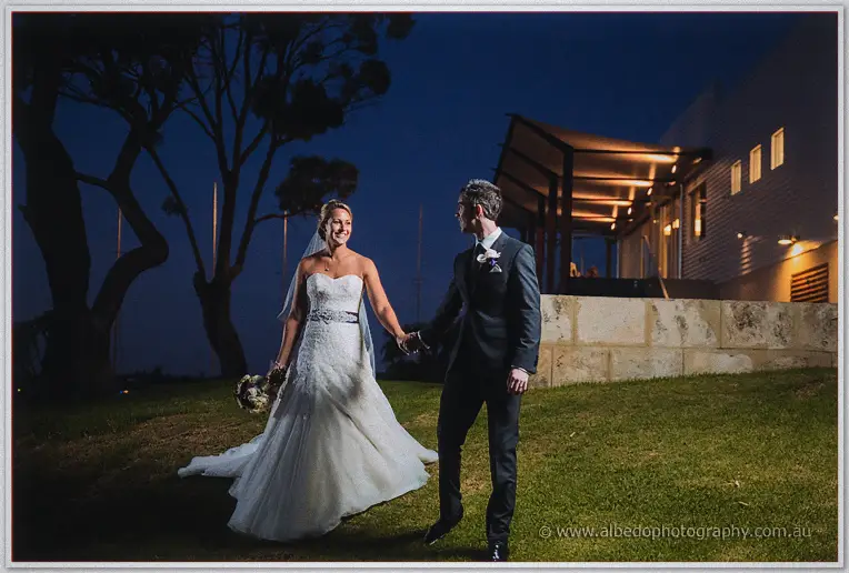 The pair cross the floodlit lawn at Royal Freshwater Bay, clubhouse glowing behind them