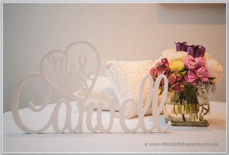A carved wooden Mr and Mrs heart sign and blush roses decorate the couple's sweetheart table