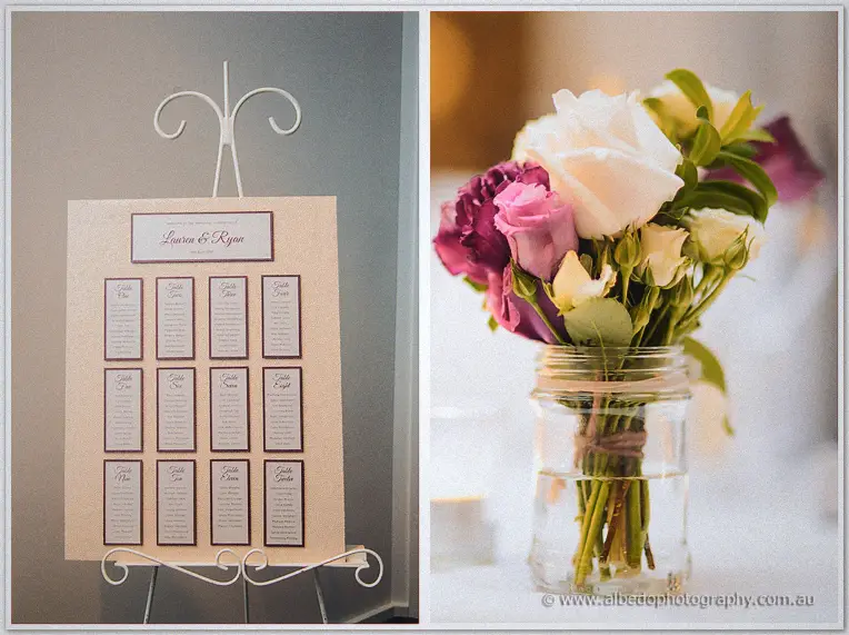 Seating plan on a white easel beside a jam jar of purple and cream roses at the reception