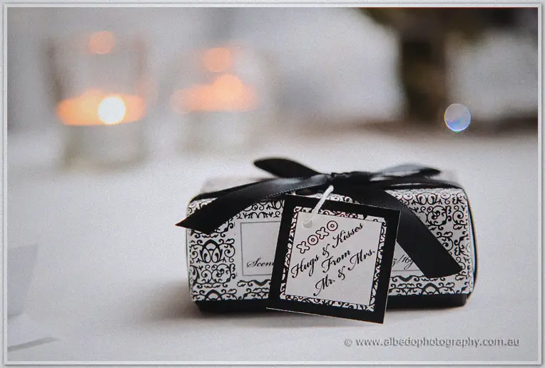A black ribboned bonbonniere tagged hugs and kisses sits on the table by candlelight