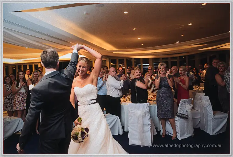 Lauren spins under Ryan's arm as guests cheer around the yacht club dance floor at night